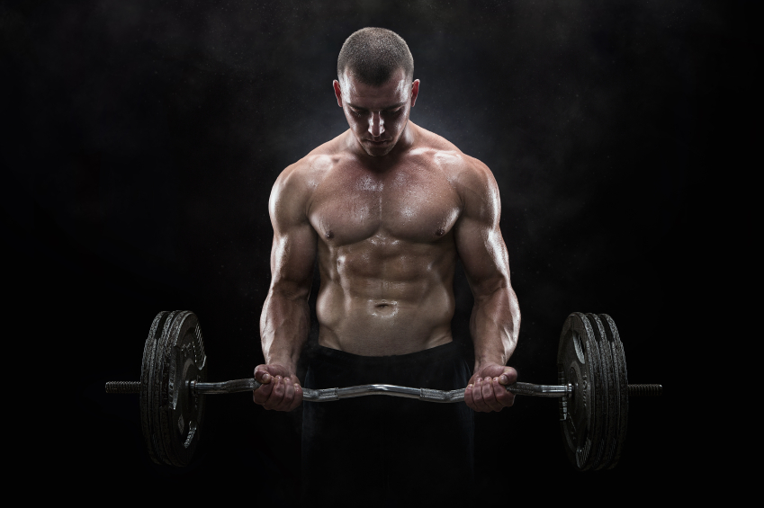 Close up of young muscular man lifting weights over dark backgro